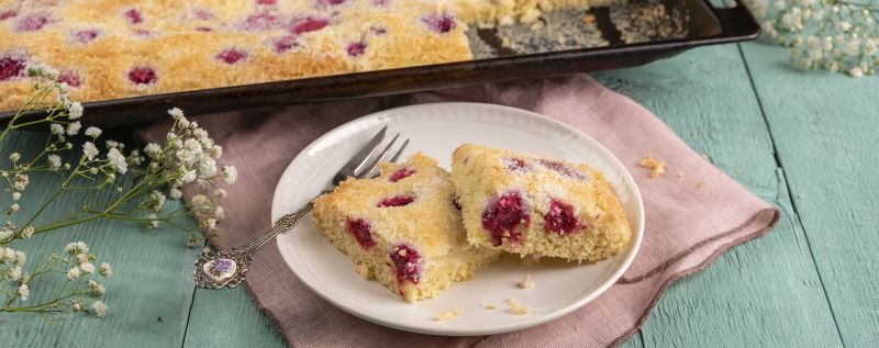 Saftiger Kokoskuchen vom Blech mit versunkenen Himbeeren.