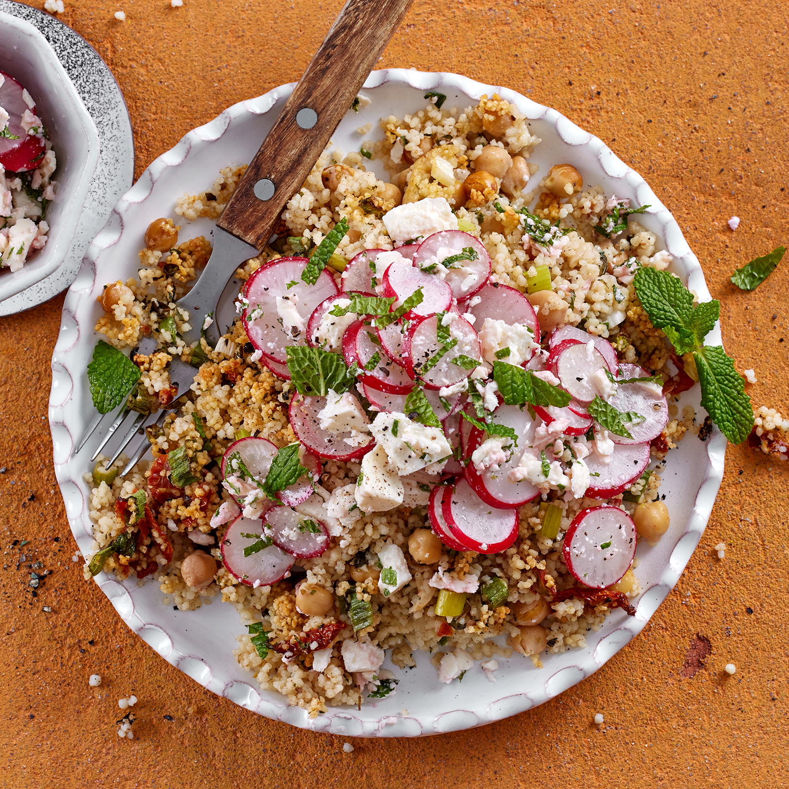 Schneller Couscousauflauf mit Kichererbsen und Radieschen-Feta-Topping, garniert mit frischer Minze.