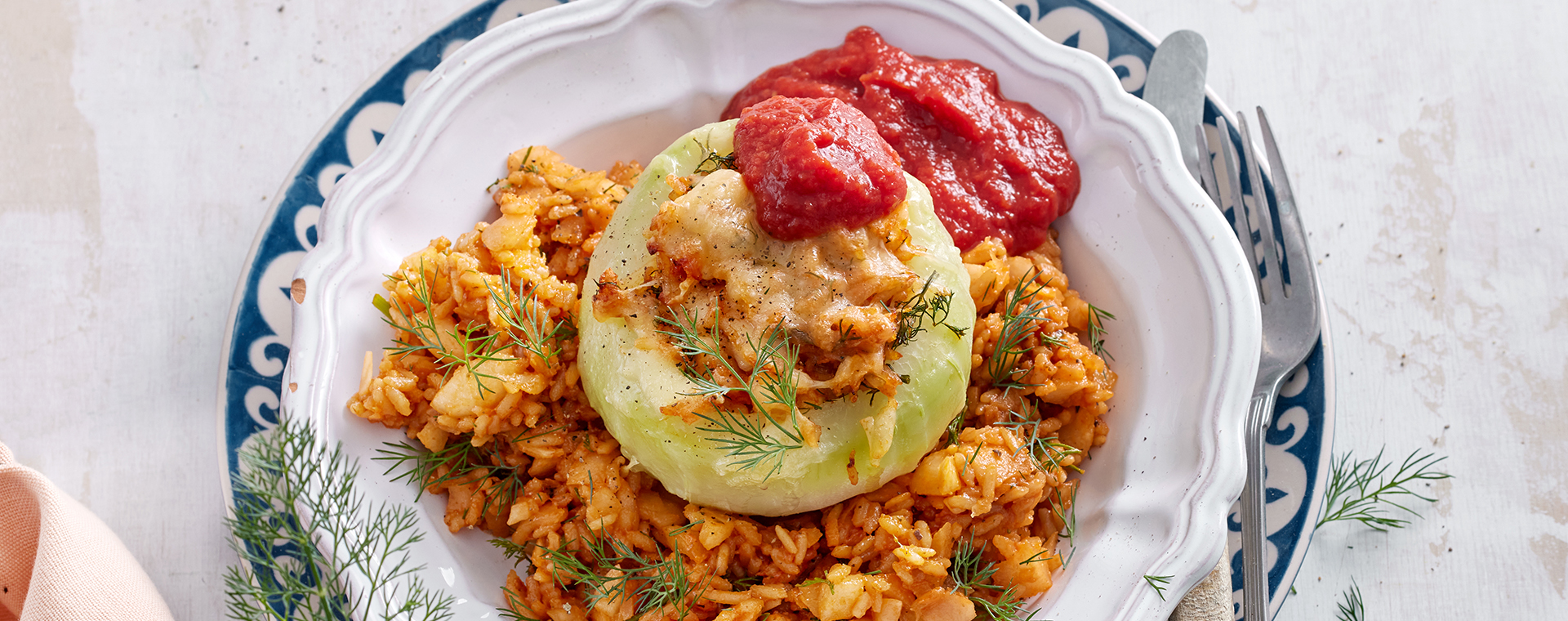 Kohlrabi mit Reisfüllung und Tomatensoße auf einem Teller.