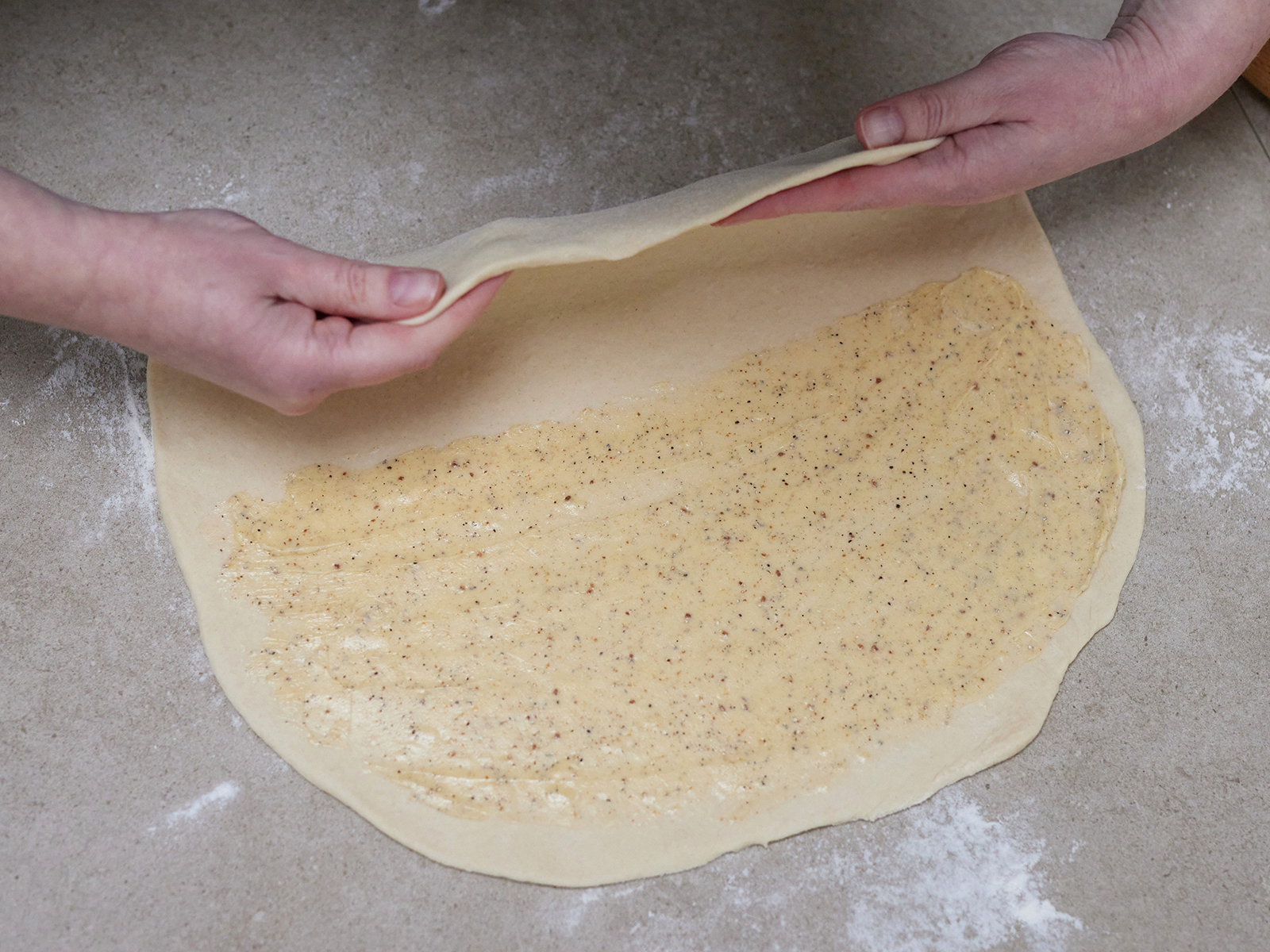 Die freie Hälfte des Hefeteigs wird über die mit Butter bestrichene Teighälfte geklappt.