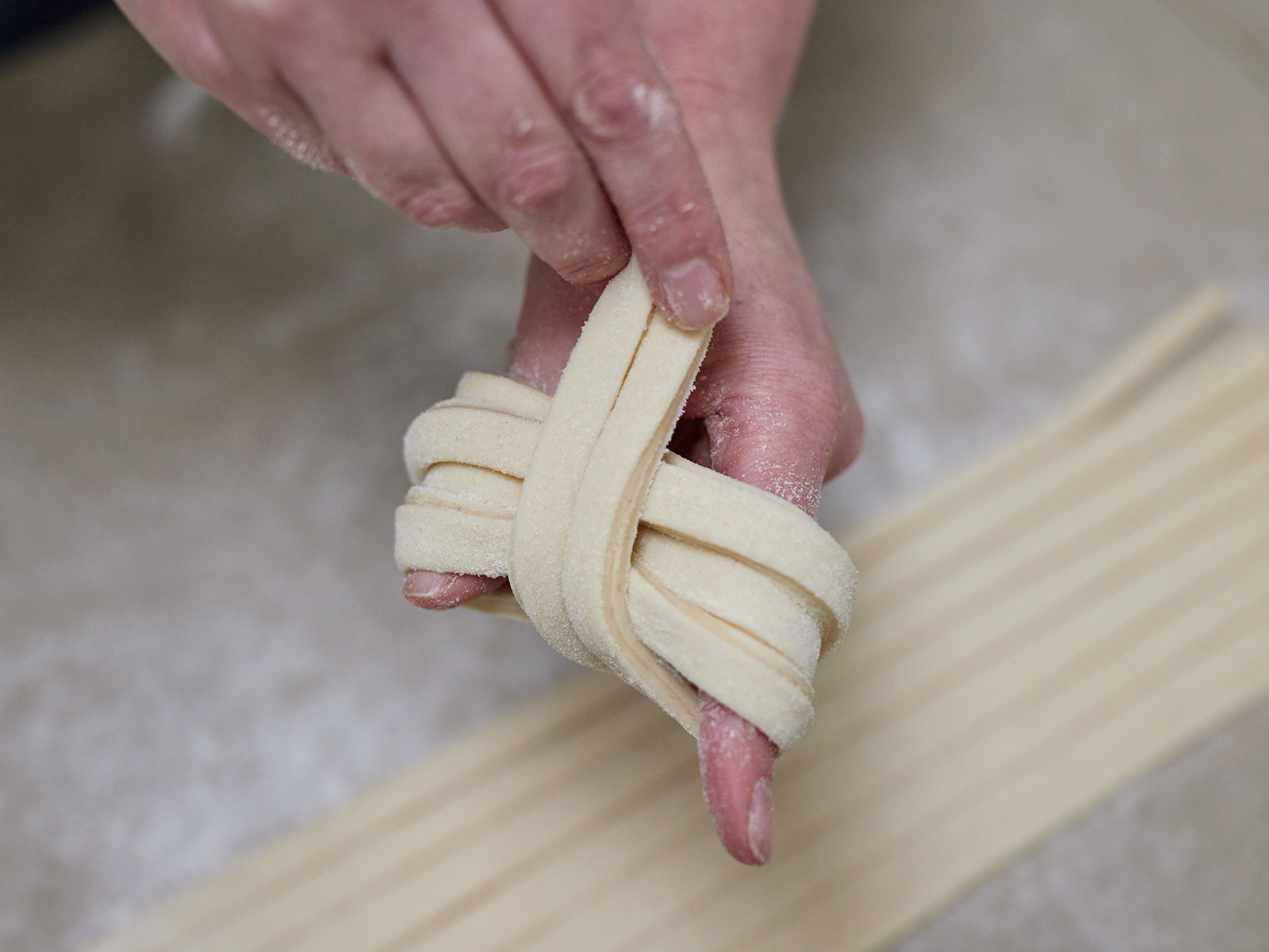 Bei der dritten Runde werden die Teigstreifen quer um die anderen gelegt, wie bei einem Knoten.